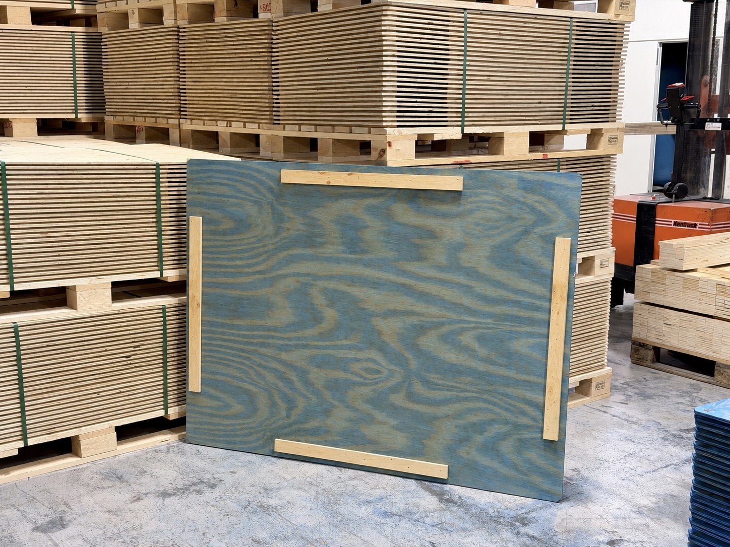 Plywoodlock med fyra trälister framför staplade plywoodlock