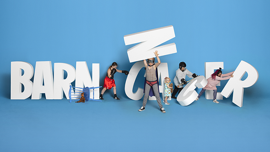Children interacting with large white letters spelling Barncancer Fonden as part of GLF community sponsoring.