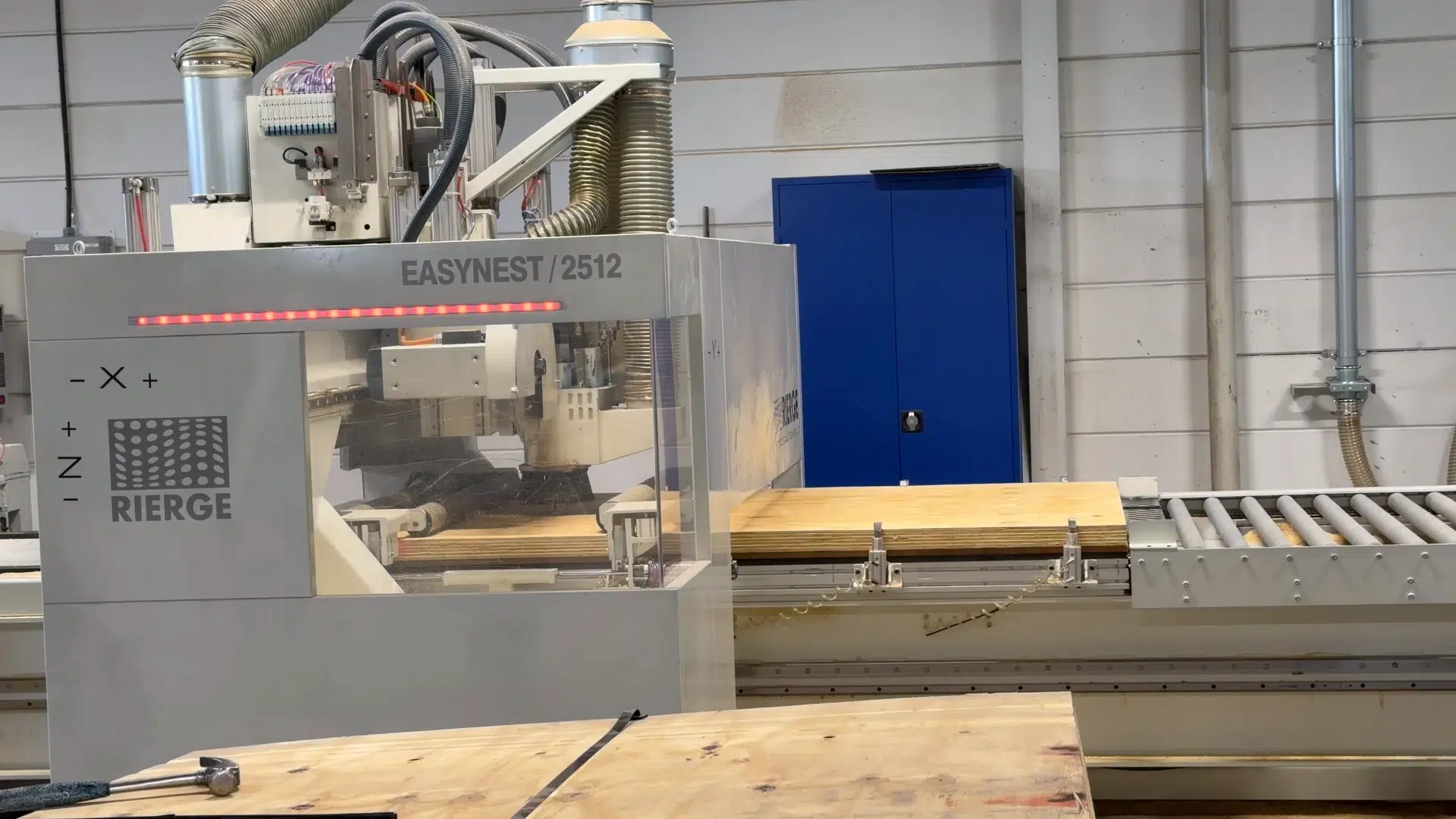 The Rierge EasyNest machine with plywood on the roller conveyor.