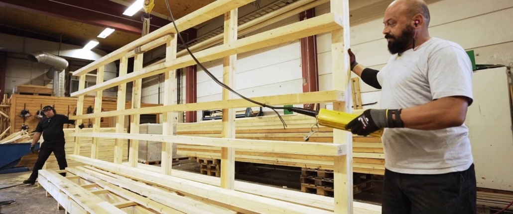 Two workers assembling a large wooden frame structure in GLF's workshop for Elmia Subcontractor.